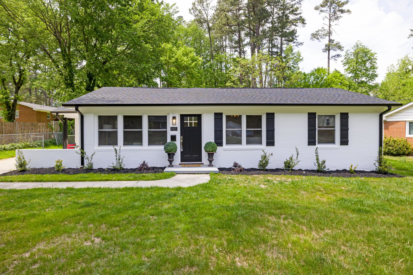 White painted house exterior with dark shutters and a green lawn