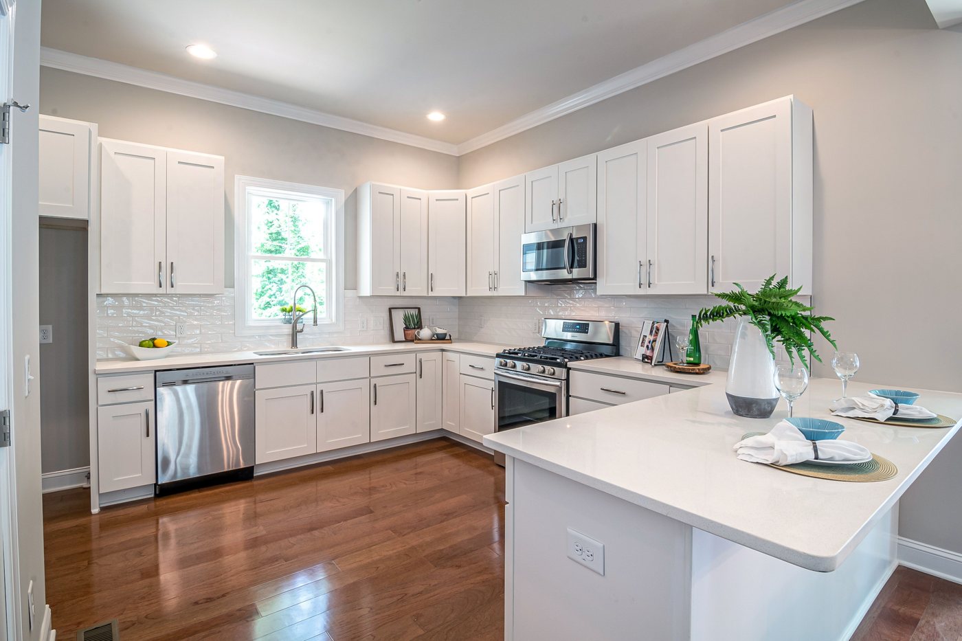 Kitchen with white painted cabinets, a light countertop and wood flooring